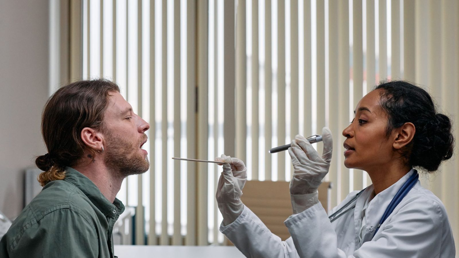 Médico examinando a garganta de uma paciente