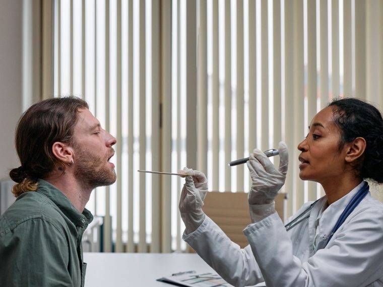 Médico examinando a garganta de uma paciente