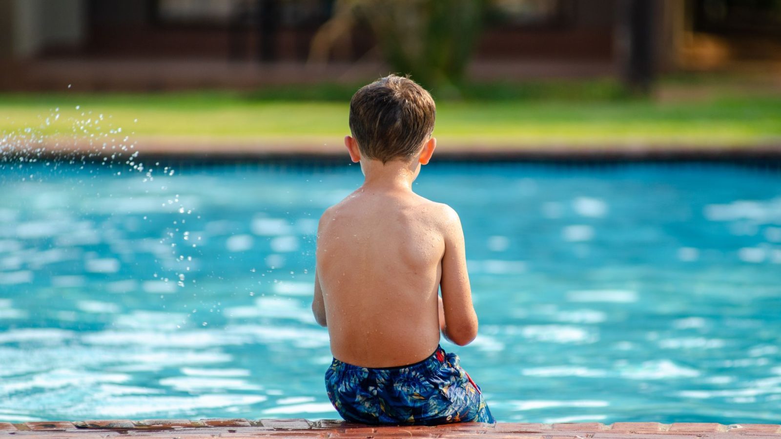 Criança nadando em piscina, ao ar livre
