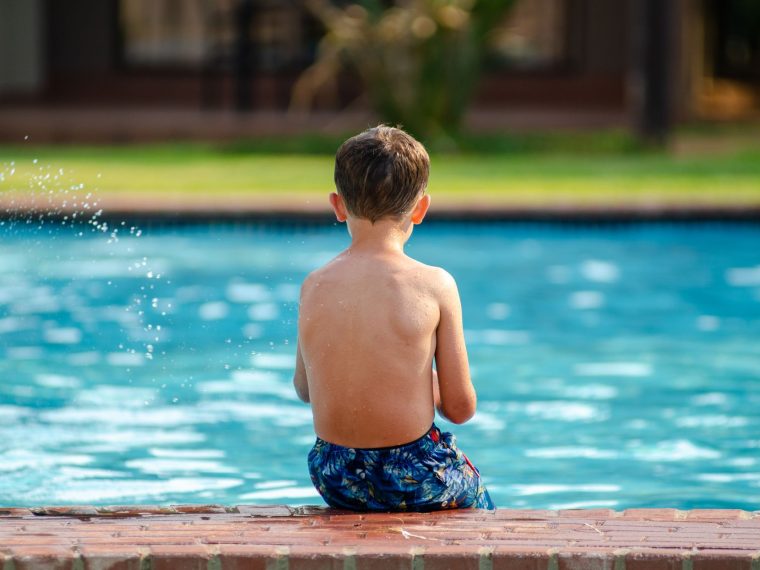 Criança nadando em piscina, ao ar livre