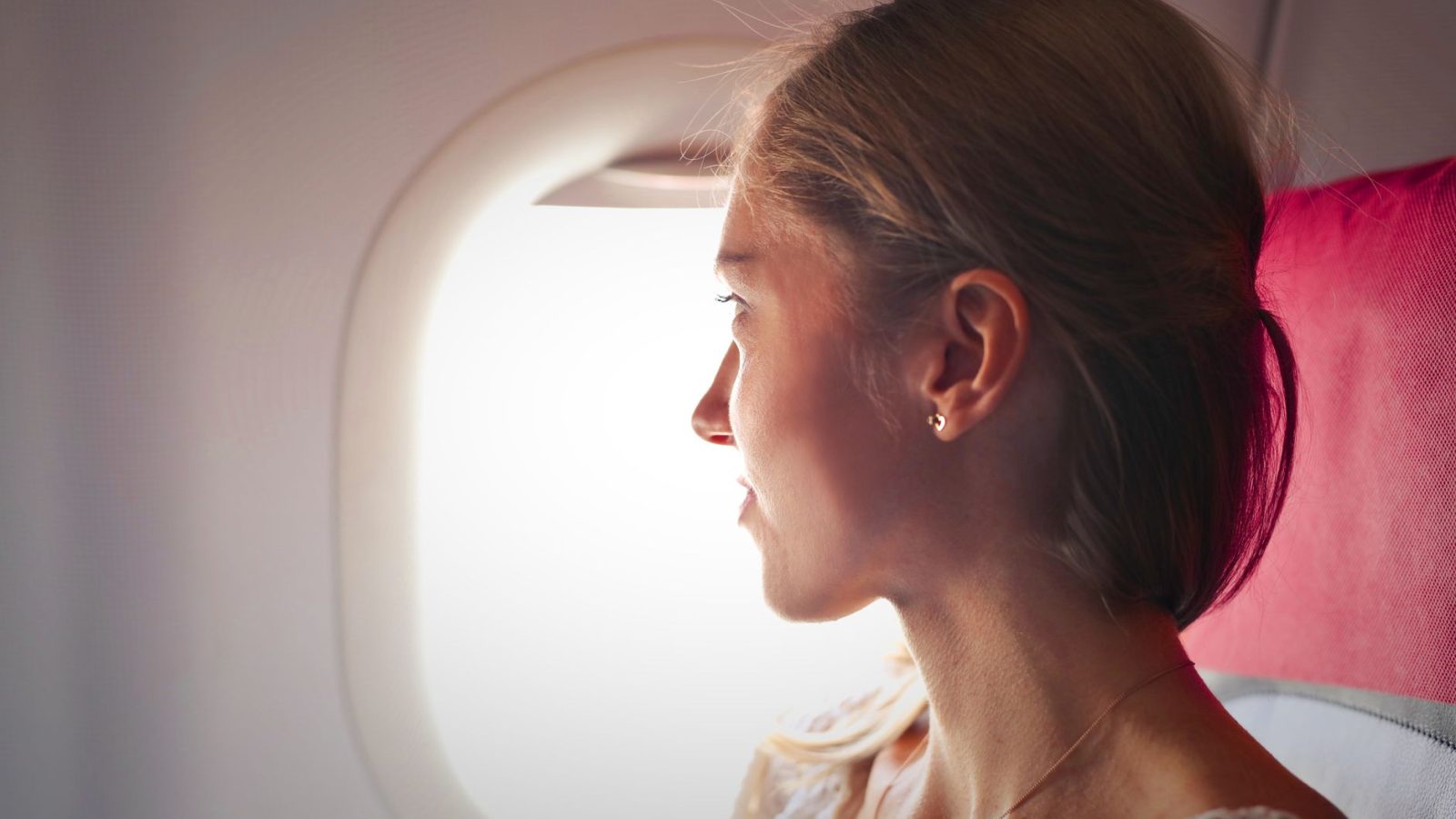 Passageira dentro de um avião, com a mão no ouvido