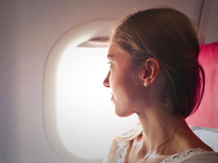 Passageira dentro de um avião, com a mão no ouvido
